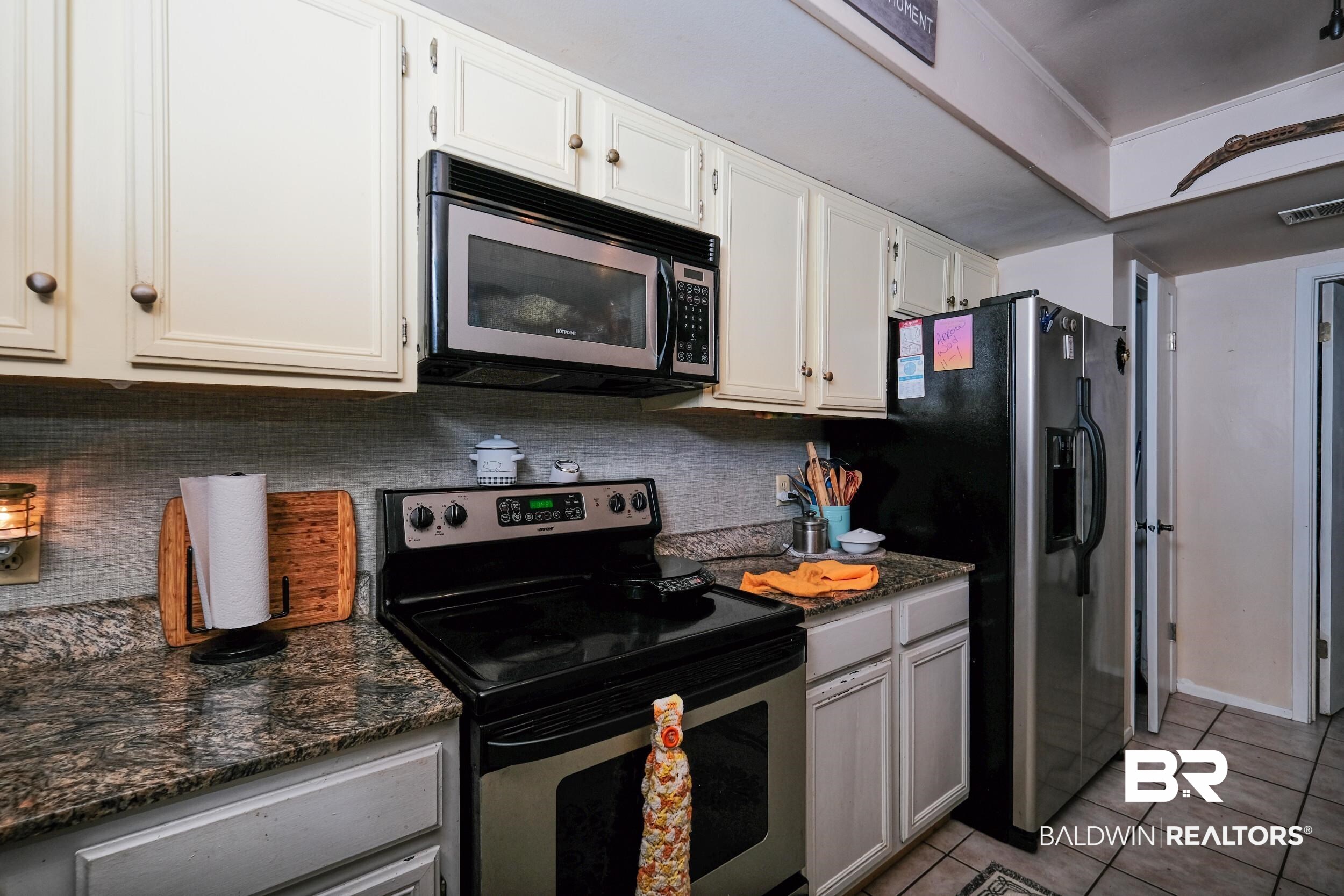 504 Ariel Avenue Foley, AL 36535 - Photo 18 of 33 Kitchen with light tile patterned flooring, white cabinetry, tasteful backsplash, dark stone counters, and stainless steel appliances
