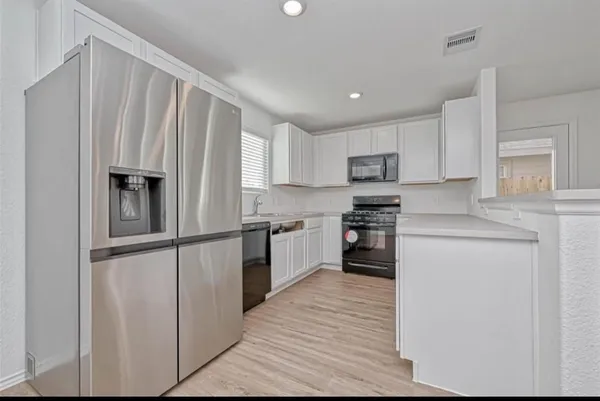 a kitchen with granite countertop white cabinets and stainless steel appliances