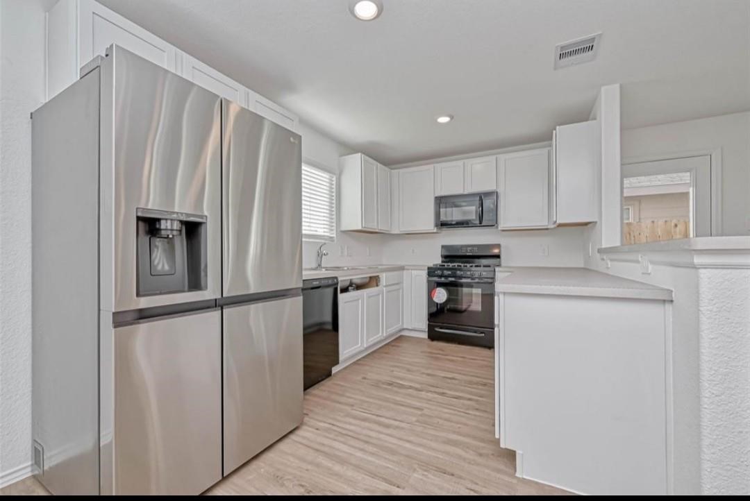1319 Vincente Court Conroe, TX 77301 - Photo 4 of 10 a kitchen with granite countertop white cabinets and stainless steel appliances
