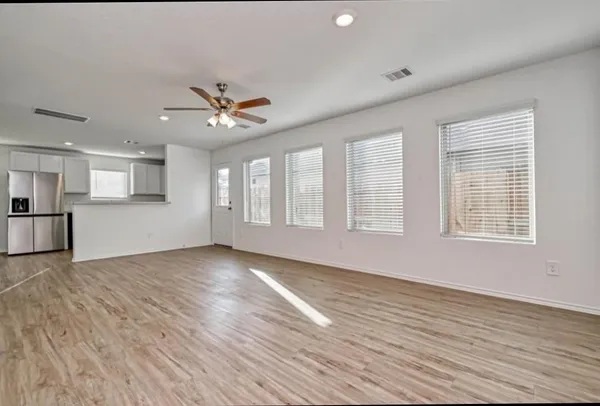 a view of an empty room with window and wooden floor