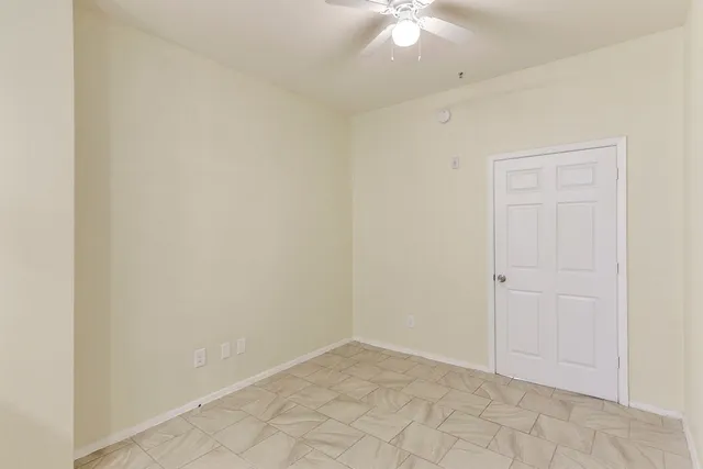 an empty room with a chandelier fan and windows
