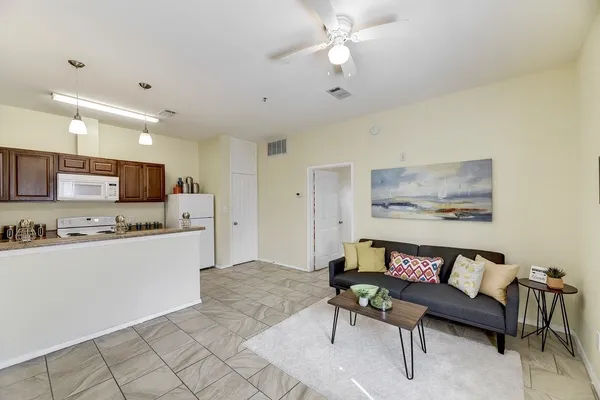 a living room with stainless steel appliances furniture and a kitchen view