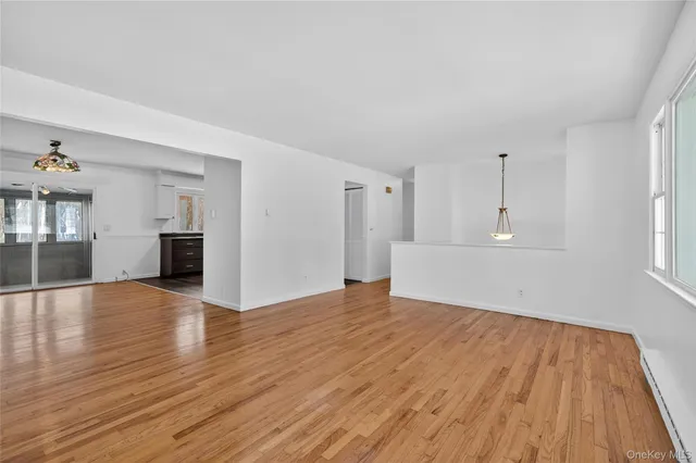 a view of empty room with wooden floor and window