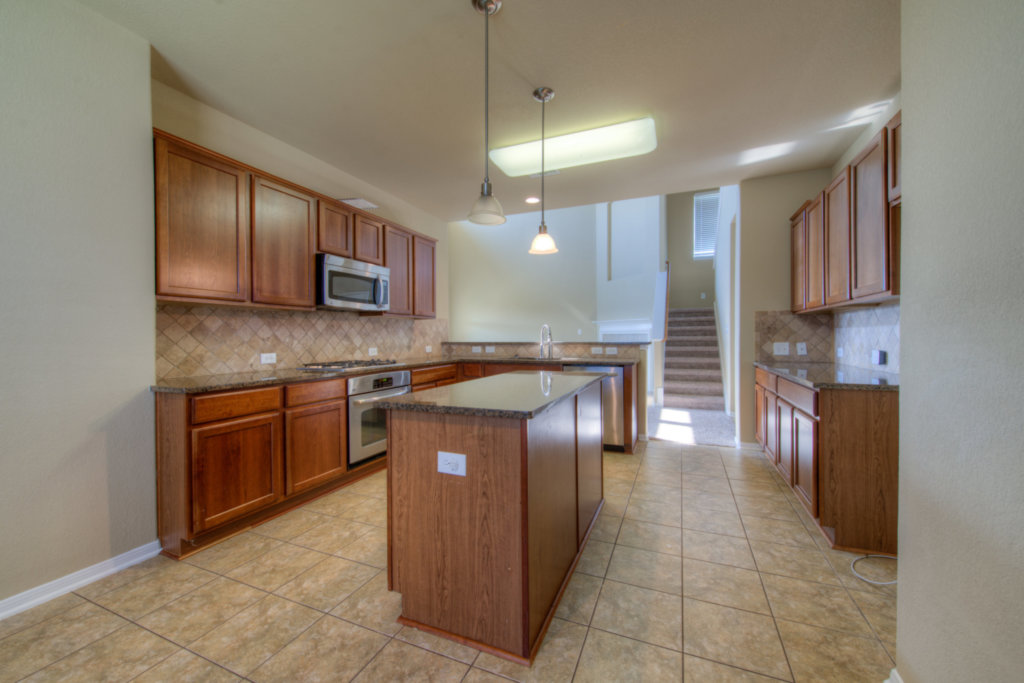 403 Limestone Trail Austin, TX 78737 - Photo 13 of 18 Culinary delights await in this modern kitchen with granite counters and rich wood cabinetry.