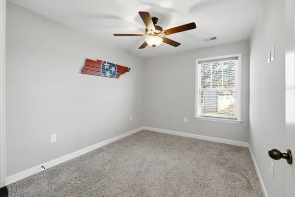 an empty room with a window and a fan