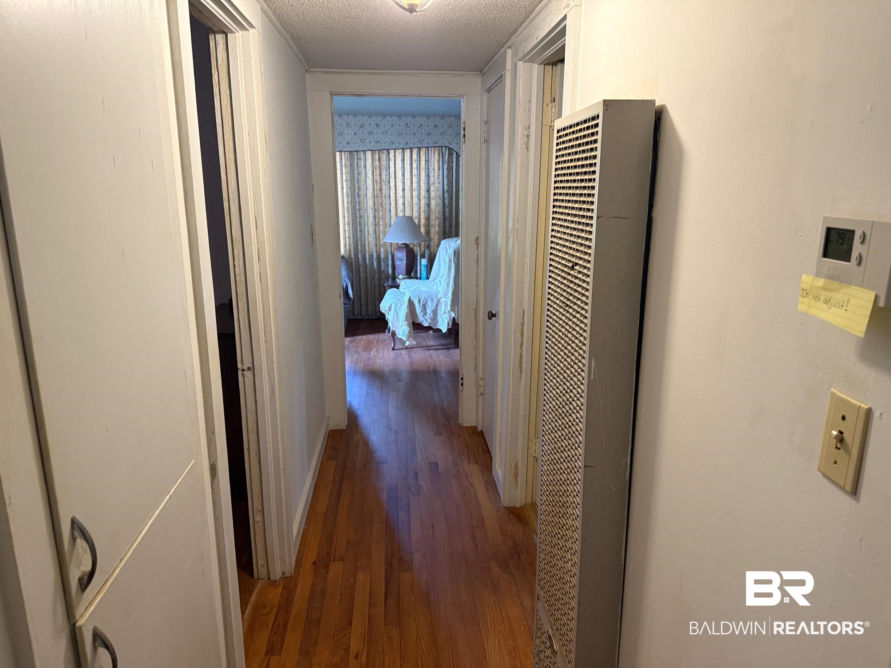 156 Pier Avenue Fairhope, AL 36532 - Photo 25 of 41 Hallway with dark wood-style floors, a heating unit, and a textured ceiling