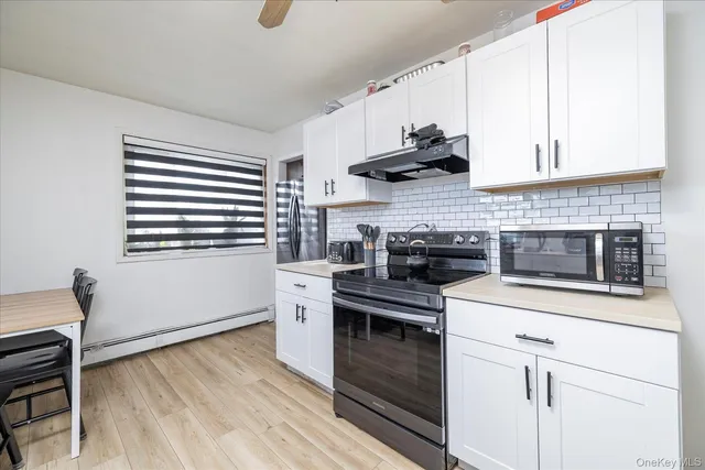 a kitchen with stainless steel appliances white cabinets and a wooden floor
