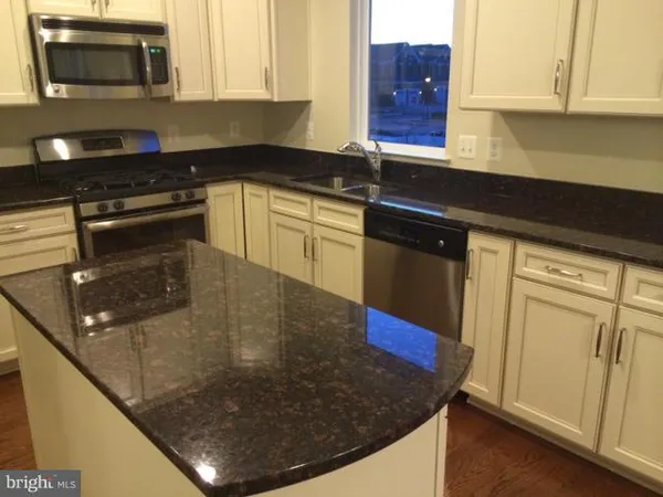 a kitchen with granite countertop white cabinets and black appliances