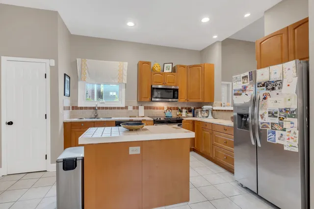 a kitchen with stainless steel appliances granite countertop a refrigerator a sink a stove a dining table and chairs
