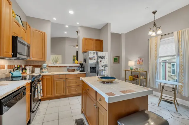 a kitchen with a stove a sink a refrigerator and chairs