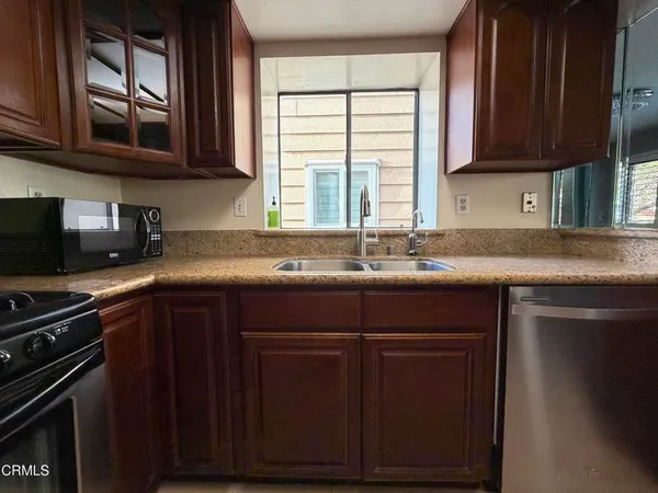 a kitchen with a sink a stove cabinets and a window