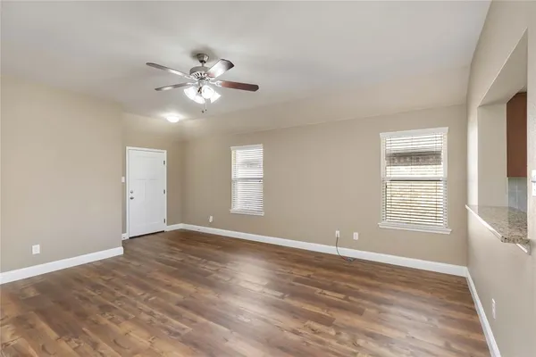 a view of an empty room with window and chandelier fan