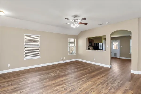 a view of an empty room with window and wooden floor