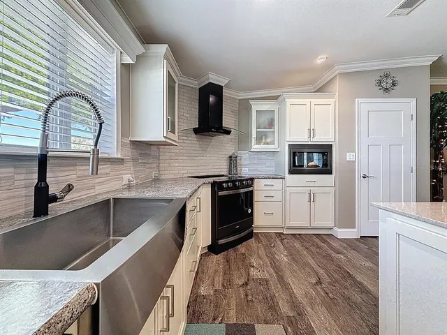 a kitchen with granite countertop a sink wooden floor and stainless steel appliances