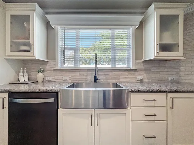 a kitchen with granite countertop white cabinets and a sink