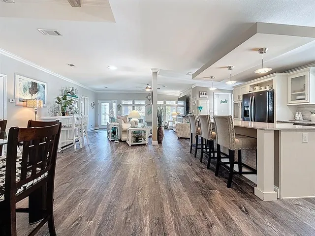 a living room with lots of furniture and kitchen view with wooden floor