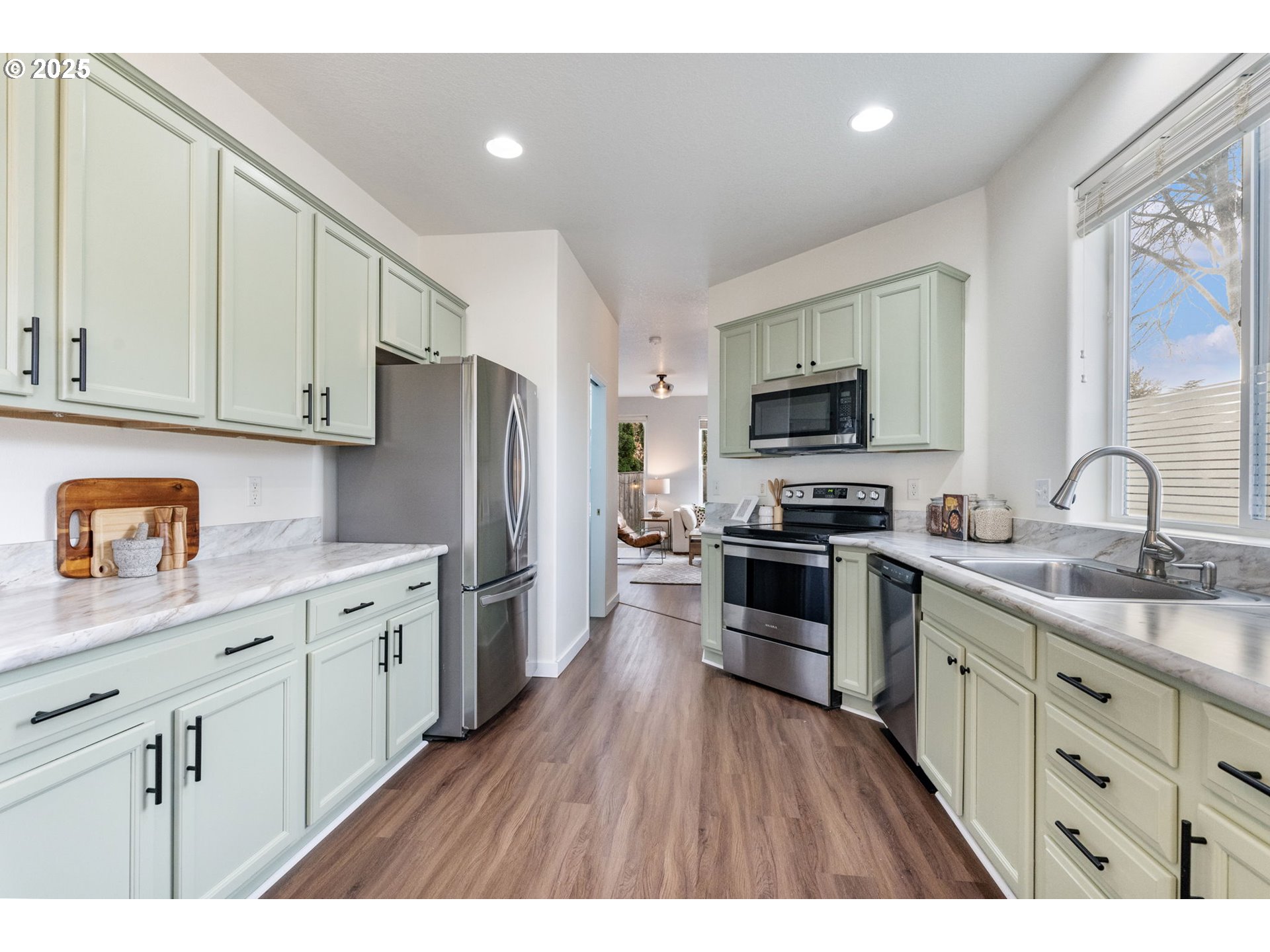 18186 Southwest Strathmoor Street Beaverton, OR 97007 - Photo 12 of 35 a kitchen with stainless steel appliances granite countertop a refrigerator a stove top oven a sink dishwasher and wooden cabinets with wooden floor
