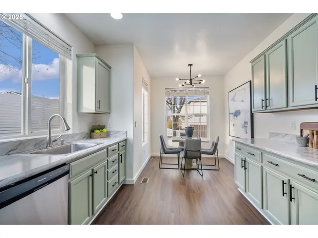 a open kitchen with cabinets a sink dishwasher a dining table and chairs with wooden floor