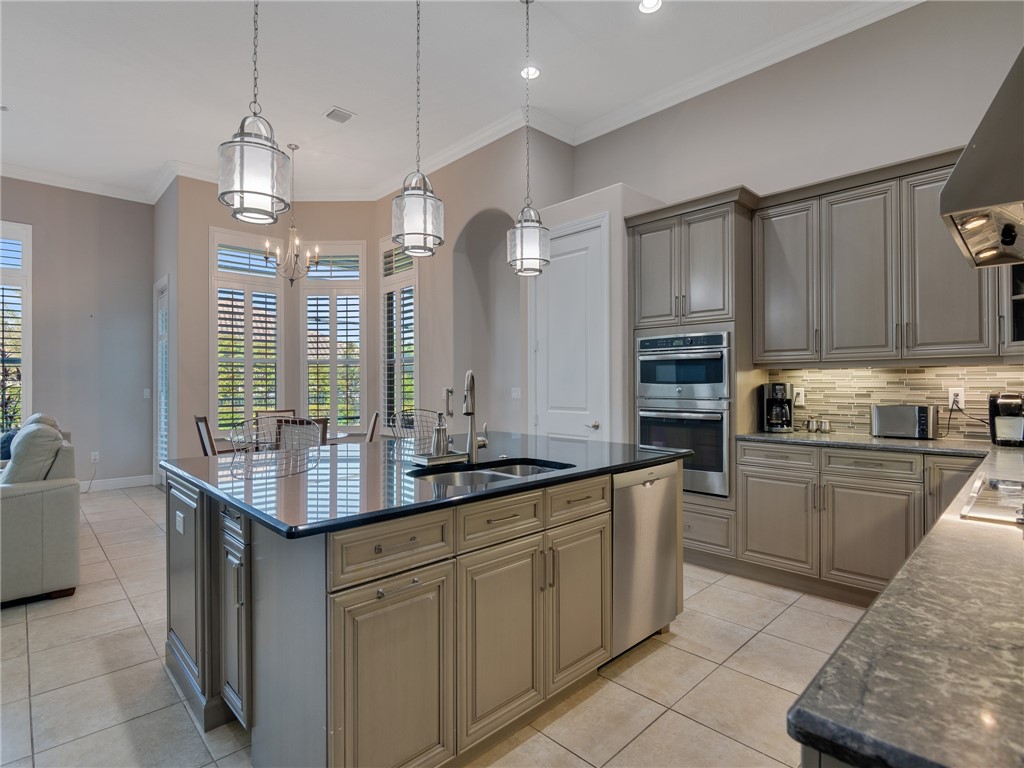 8260 Halbert Lane Vero Beach, FL 32968 - Photo 11 of 36 a kitchen with kitchen island granite countertop a sink a stove and cabinets