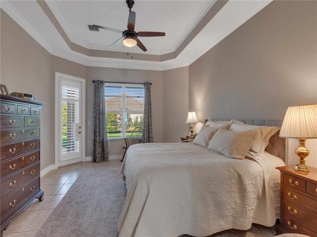 8260 Halbert Lane Vero Beach, FL 32968 - Photo 18 of 36 a spacious bedroom with a bed a dresser and a chandelier
