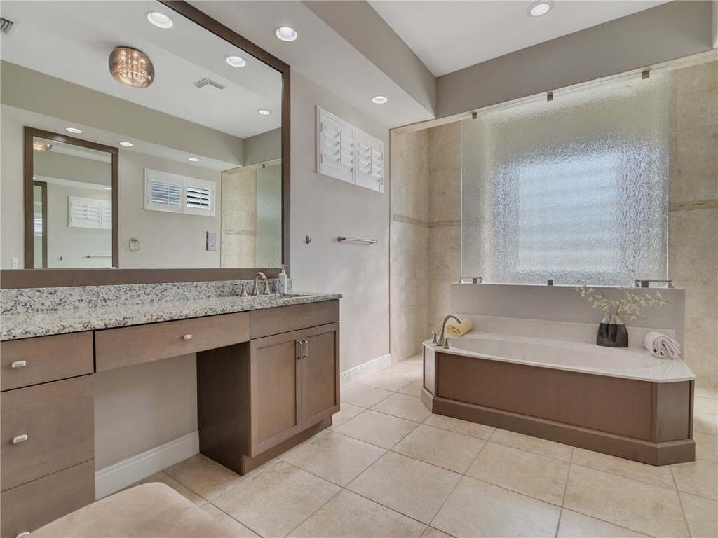8260 Halbert Lane Vero Beach, FL 32968 - Photo 19 of 36 a bathroom with a granite countertop bathtub sink vanity and mirror