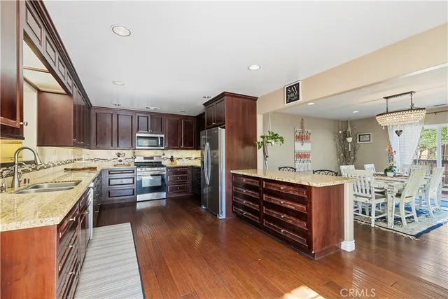 a kitchen with stainless steel appliances kitchen island granite countertop a stove refrigerator and cabinets