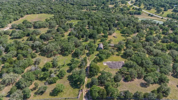 an aerial view of residential house with outdoor space and trees all around