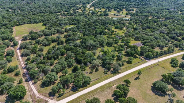 an aerial view of residential house with outdoor space and trees all around