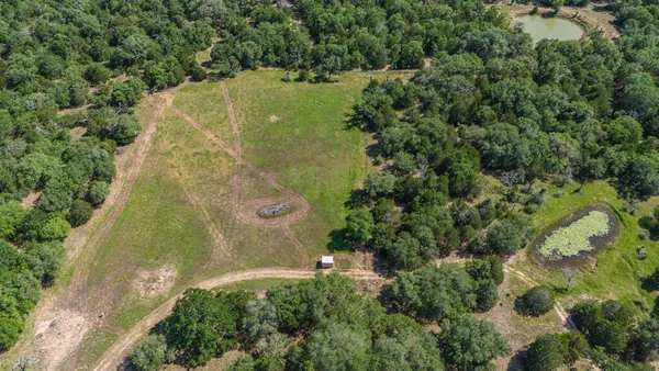 an aerial view of residential houses with outdoor space and trees