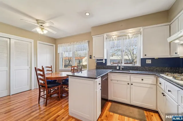 a kitchen with stainless steel appliances granite countertop a table chairs sink and cabinets
