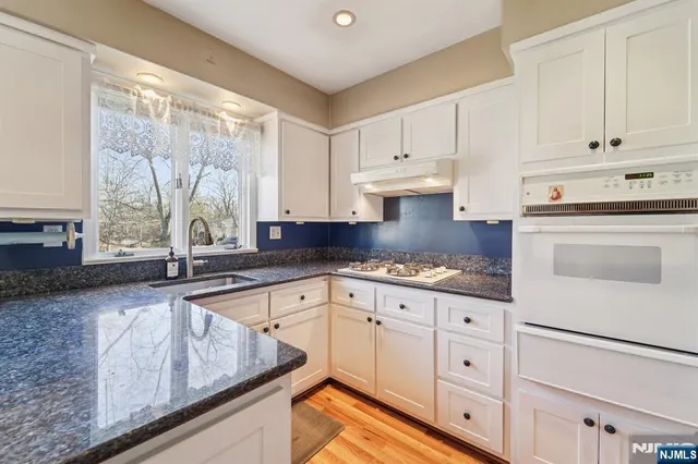 a kitchen with granite countertop white cabinets and white appliances