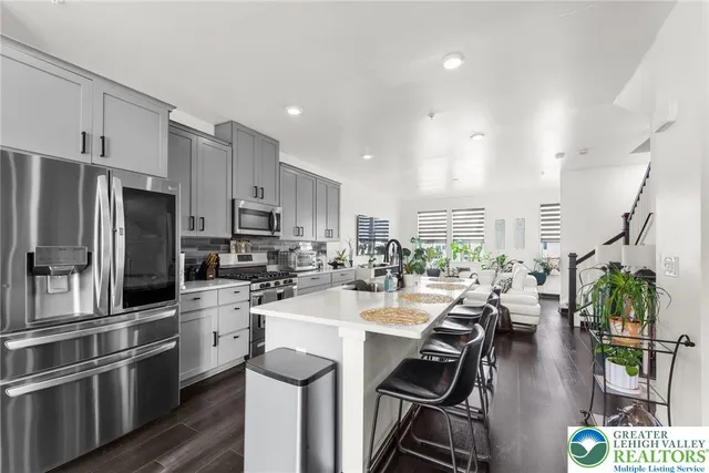 a kitchen with stainless steel appliances a stove a sink a refrigerator white cabinets and couches