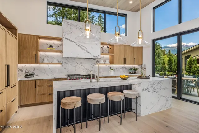 a living room with couches chairs and kitchen view with wooden floor