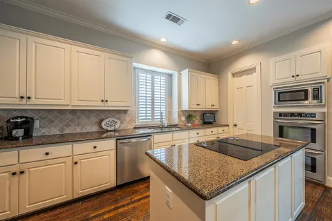 a kitchen with granite countertop white cabinets and stainless steel appliances