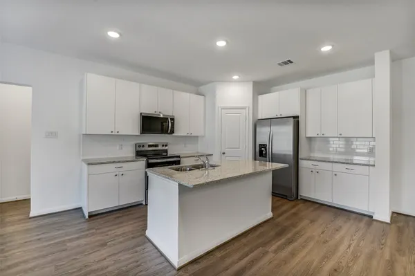 a kitchen with a sink a stove a refrigerator and white cabinets