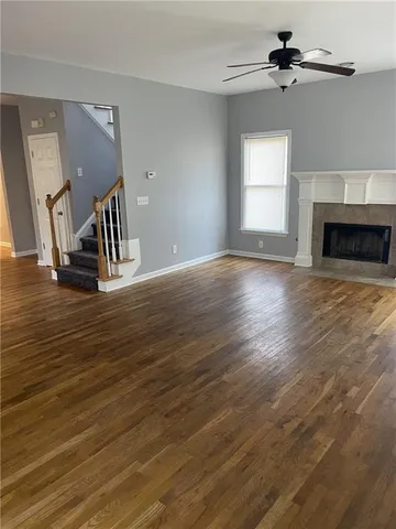 a view of an empty room with wooden floor fireplace and a window