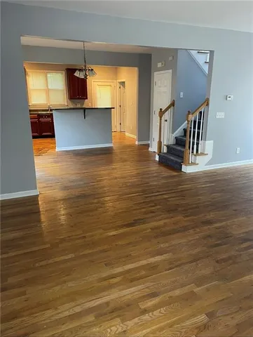 a view of kitchen and empty room with wooden floor