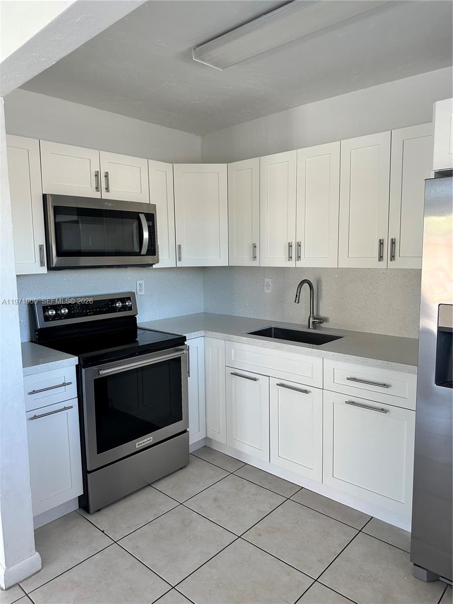 543 Southwest 37th Avenue, Unit 4 Miami, FL 33135 - Photo 9 of 12 a kitchen with white cabinets and stainless steel appliances