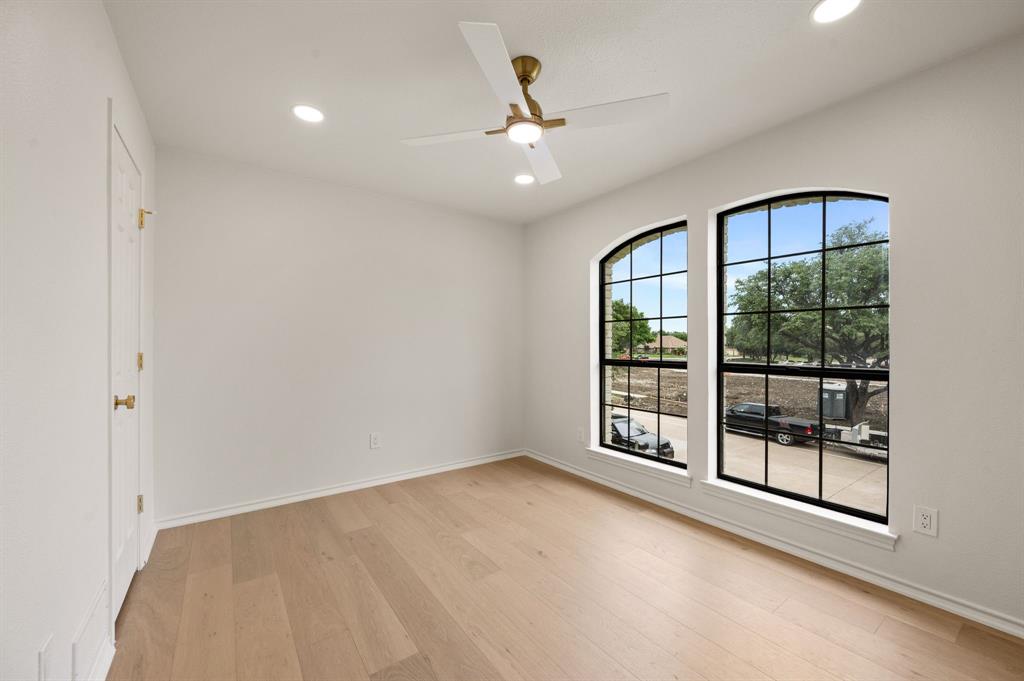 6403 Genstar Lane Dallas, TX 75252 - Photo 25 of 34 Light-filled room featuring wood-finish flooring, two arched windows with black grilles, recessed lighting, and a ceiling fan with integrated light