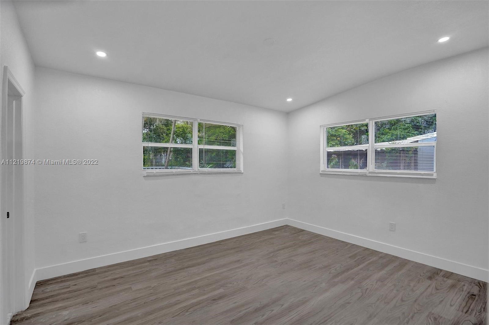 369 Northeast 158th Street Miami, FL 33162 - Photo 19 of 58 an empty room with wooden floor and windows