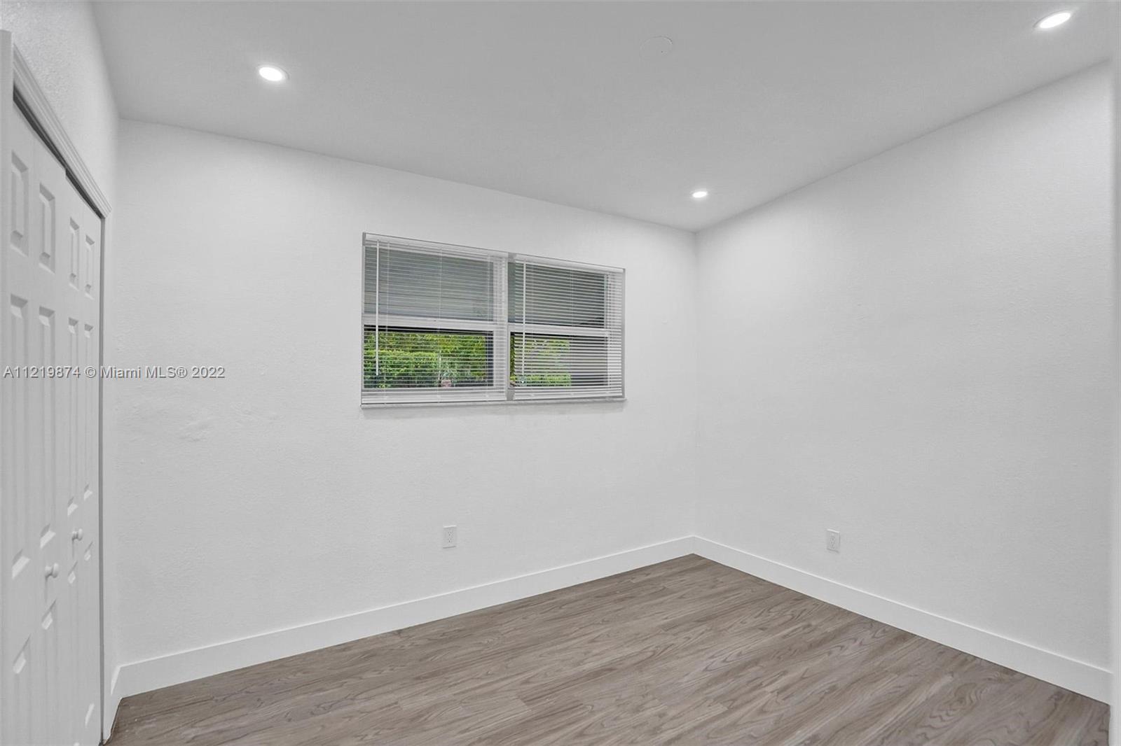 369 Northeast 158th Street Miami, FL 33162 - Photo 31 of 58 a view of an empty room with wooden floor and a window
