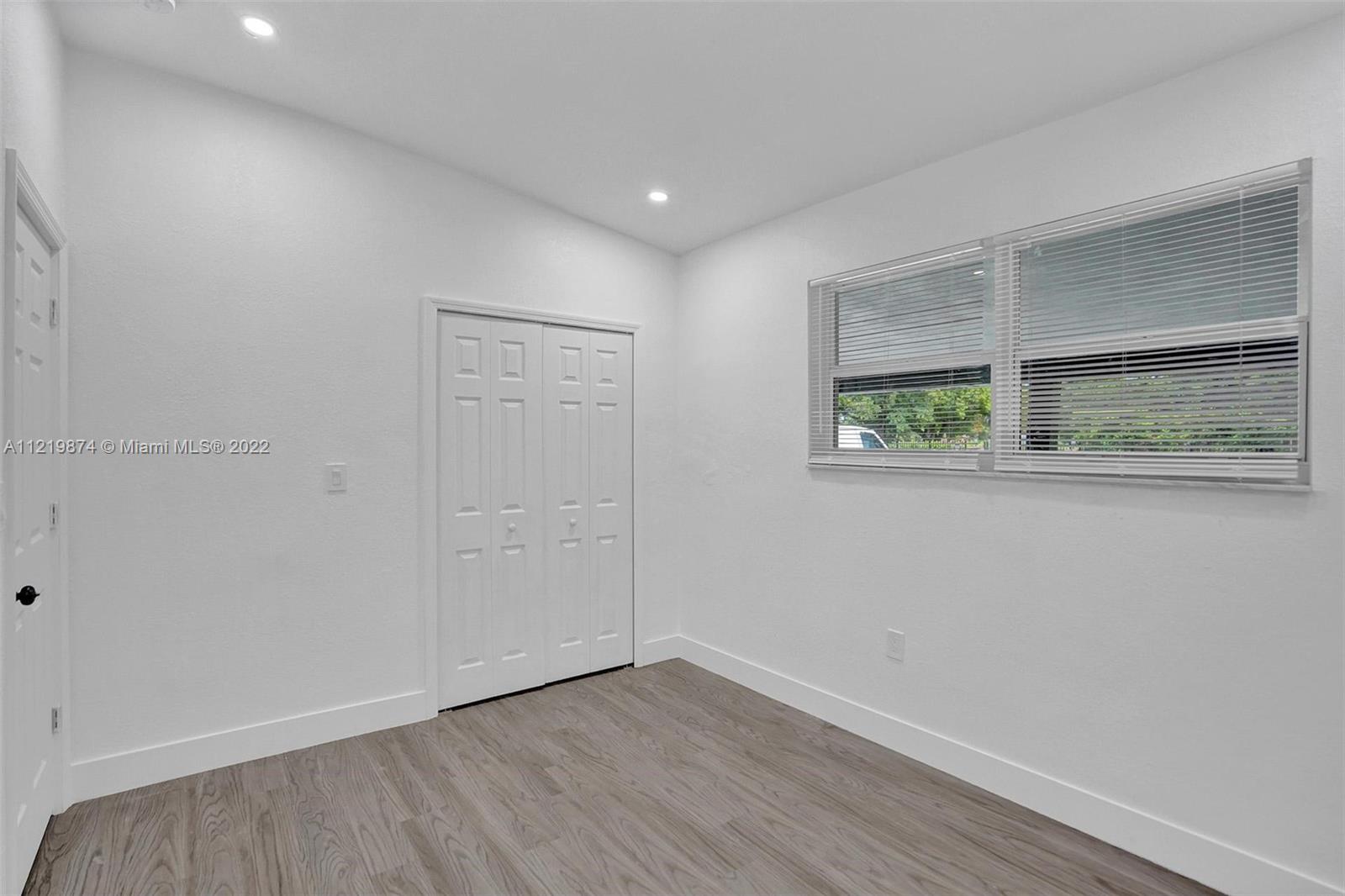 369 Northeast 158th Street Miami, FL 33162 - Photo 32 of 58 an empty room with wooden floor and windows