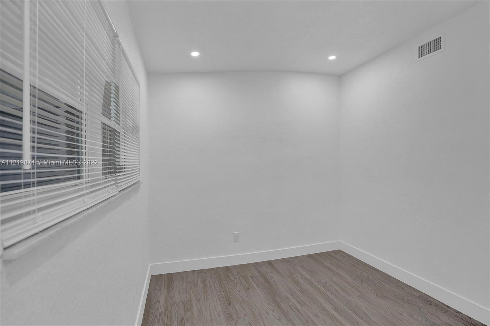 369 Northeast 158th Street Miami, FL 33162 - Photo 34 of 58 a view of an empty room with wooden floor and a window