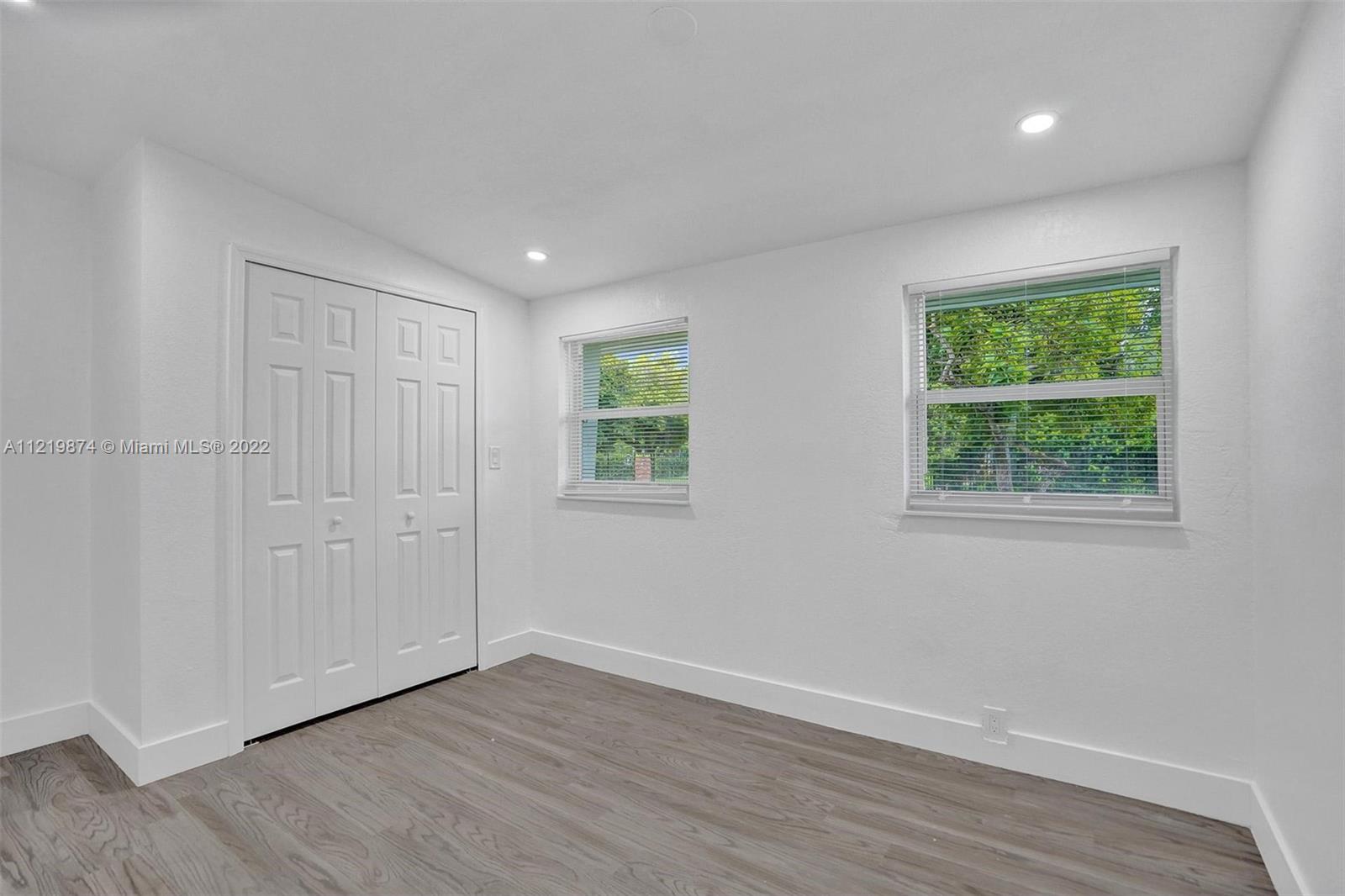 369 Northeast 158th Street Miami, FL 33162 - Photo 40 of 58 an empty room with wooden floor and windows
