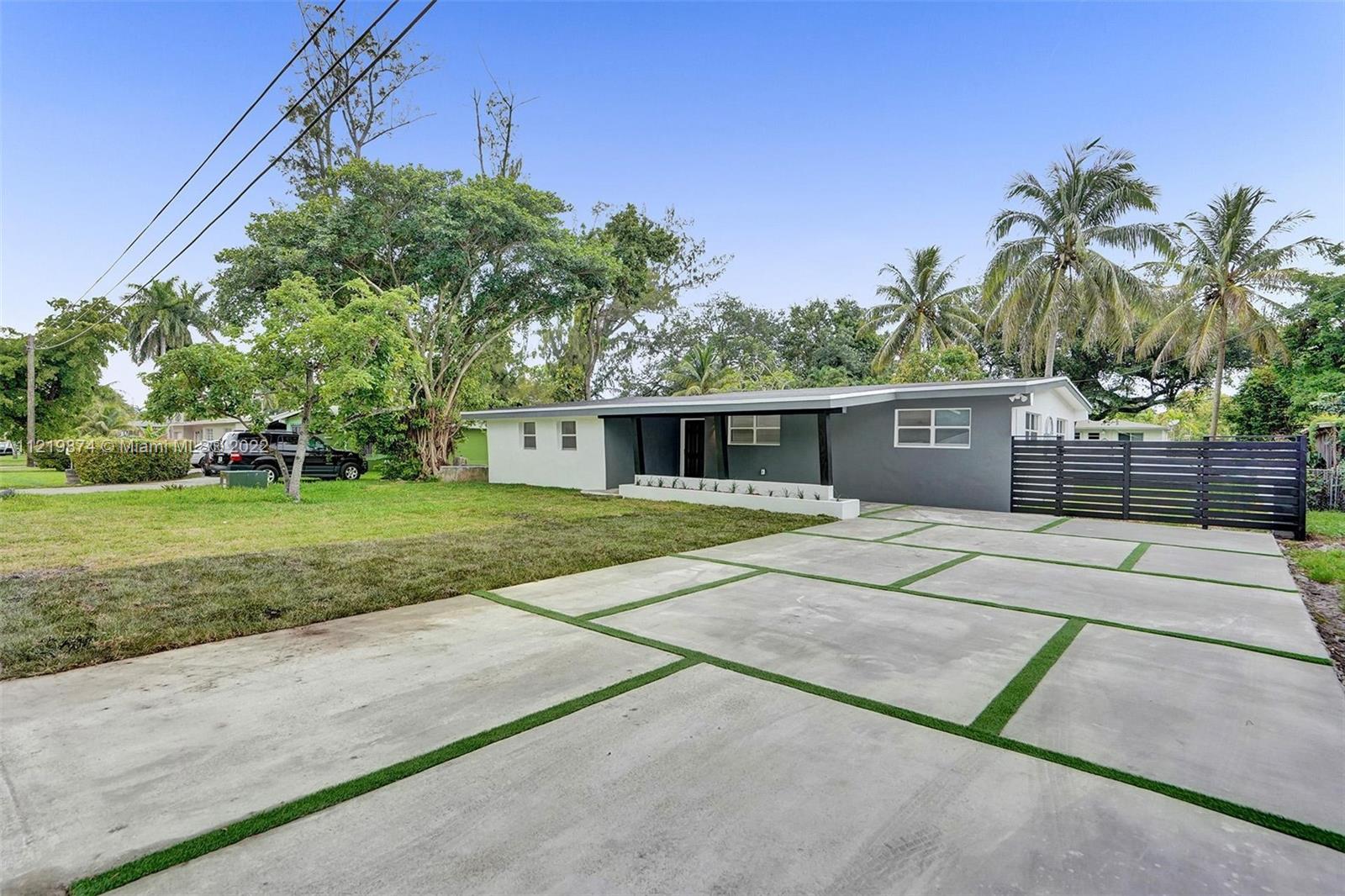 369 Northeast 158th Street Miami, FL 33162 - Photo 5 of 58 a front view of a house with a yard and garage