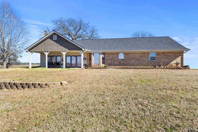 a view of a house with backyard and trees