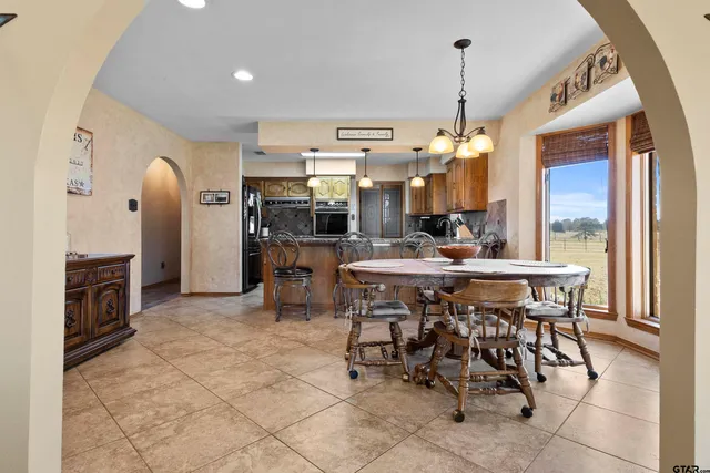 a dining hall with stainless steel appliances kitchen island granite countertop a table and chairs in it