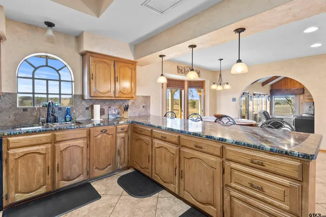 a large kitchen with stainless steel appliances granite countertop a stove a sink and a large window