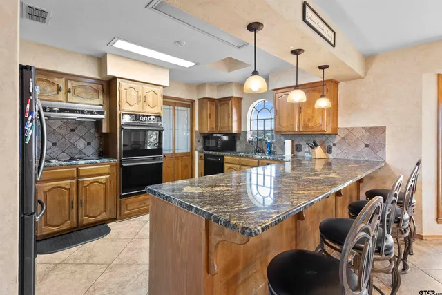 a kitchen with stainless steel appliances granite countertop a sink a stove and a wooden cabinets