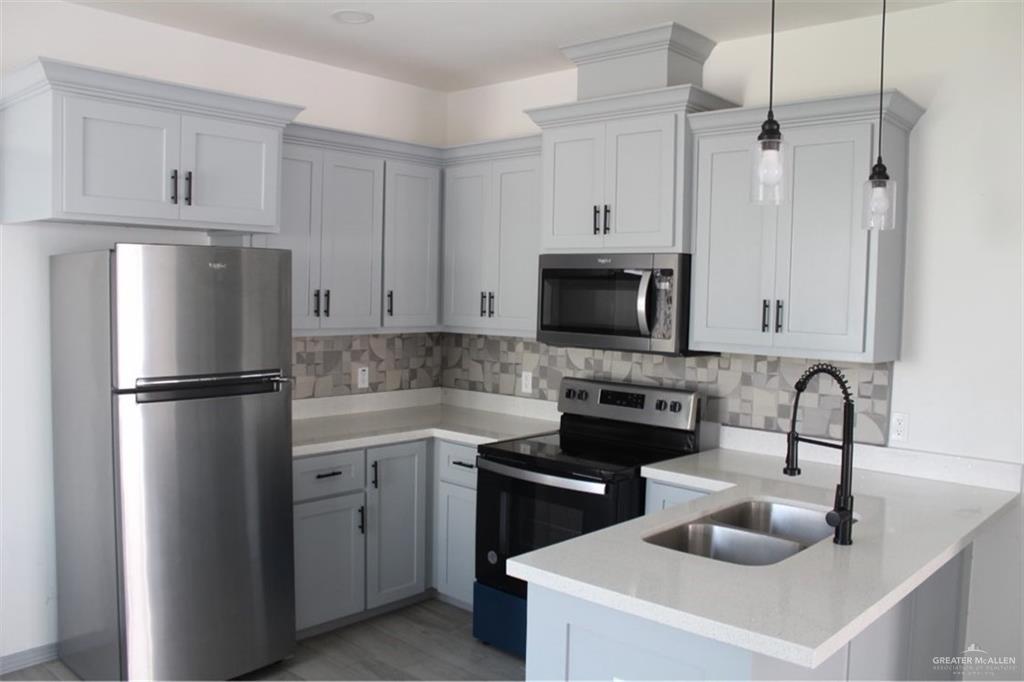 5609 Ozark Avenue, Unit 1 Mission, TX 78573 - Photo 5 of 8 a kitchen with stainless steel appliances a refrigerator sink and white cabinets